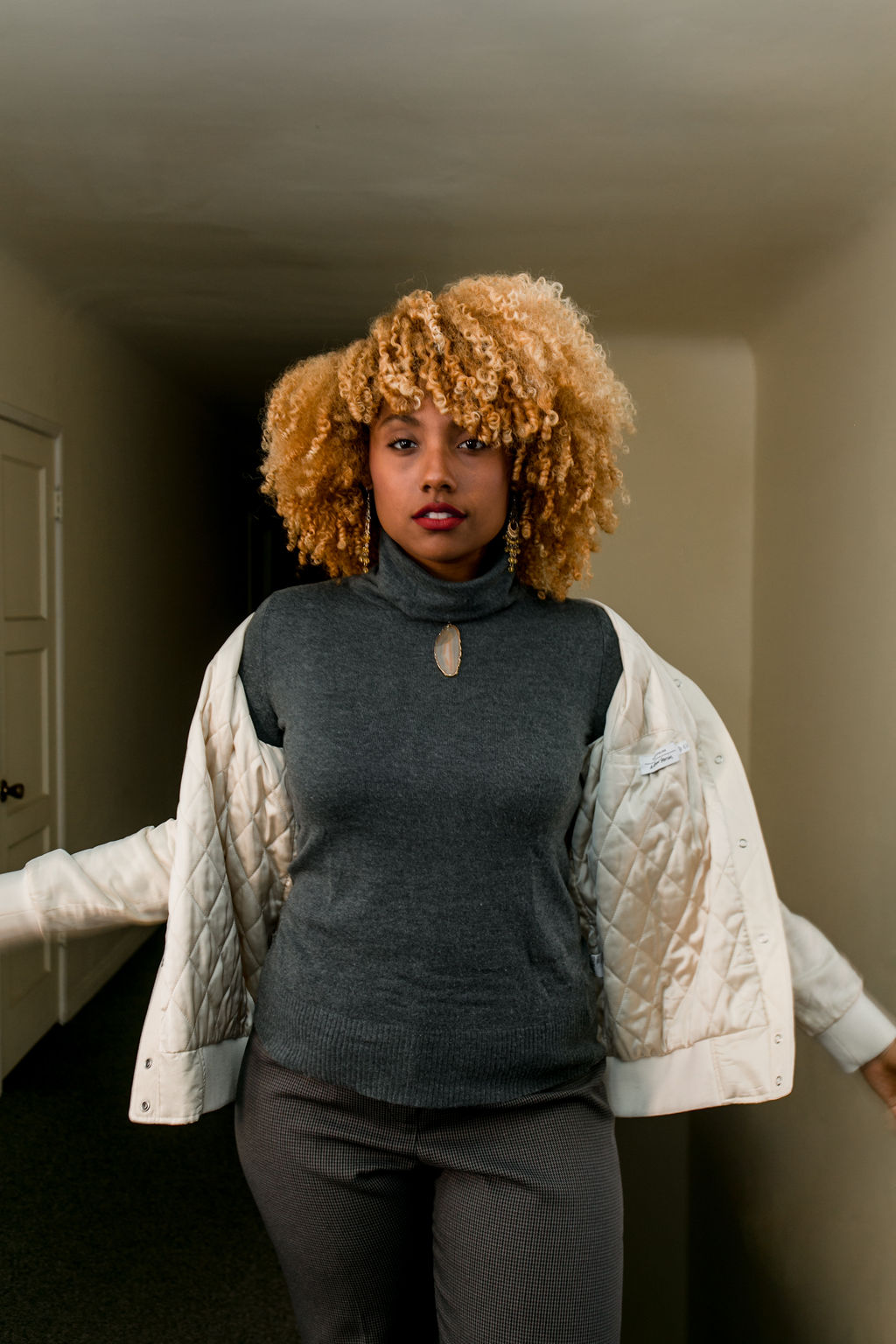 woman wearing slacks with sneakers and a blonde curl fro