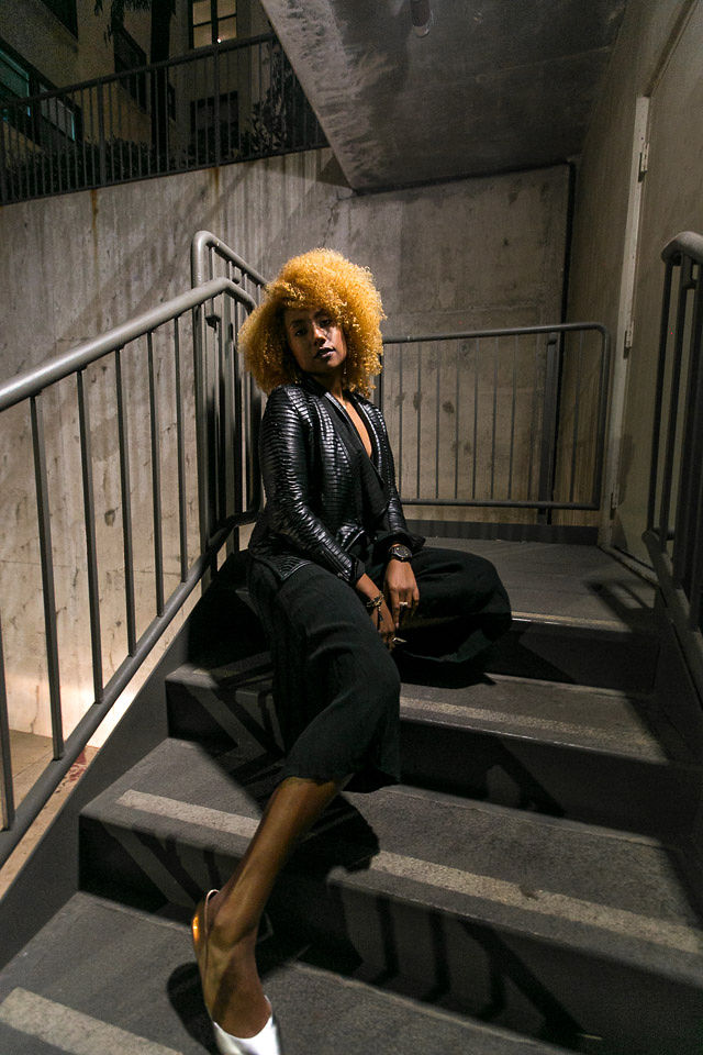 woman sitting on stairs wearing all black outfit and silver shoes